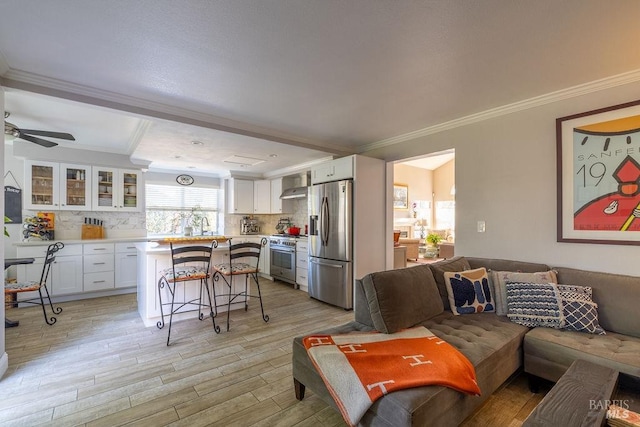 living room with light wood-style floors, ornamental molding, and a ceiling fan