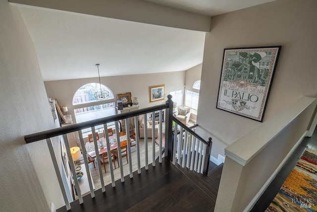 stairway with an inviting chandelier, baseboards, a wealth of natural light, and wood finished floors