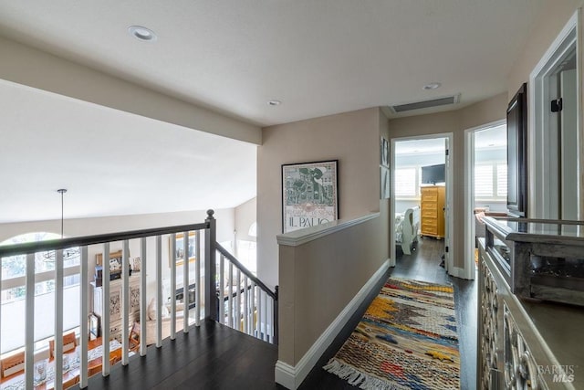 corridor featuring baseboards, visible vents, wood finished floors, an upstairs landing, and recessed lighting