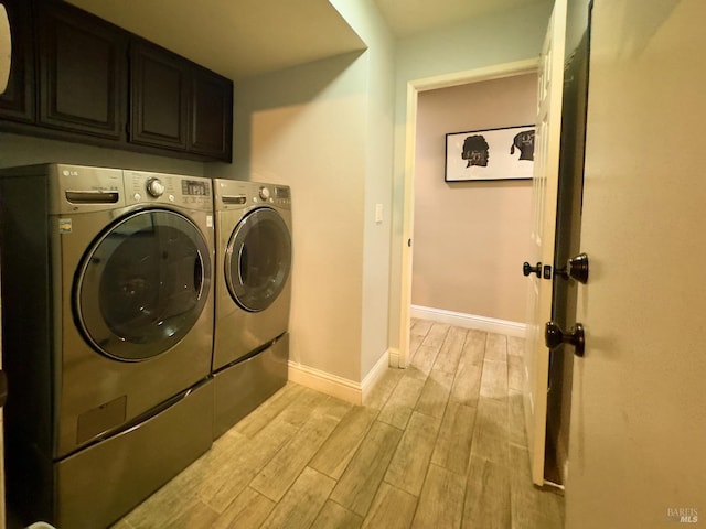 clothes washing area with washing machine and dryer, cabinet space, baseboards, and wood finish floors