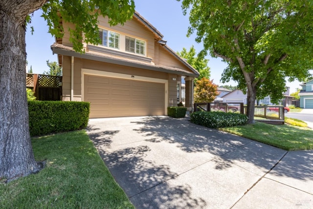 traditional-style home with a garage, concrete driveway, and fence