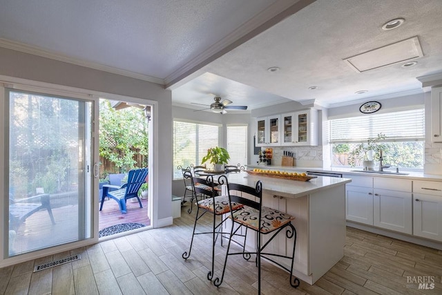 kitchen with light countertops, white cabinets, visible vents, and a kitchen bar