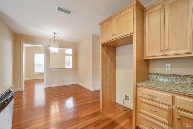 kitchen featuring visible vents, dishwasher, light wood-style flooring, light stone counters, and decorative light fixtures