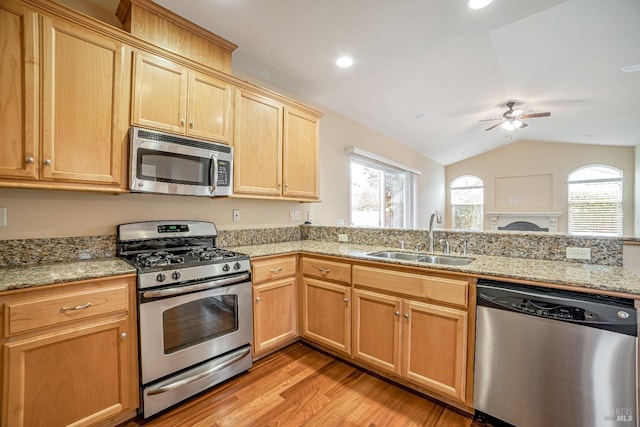 kitchen with light wood-style flooring, stainless steel appliances, a sink, a ceiling fan, and vaulted ceiling