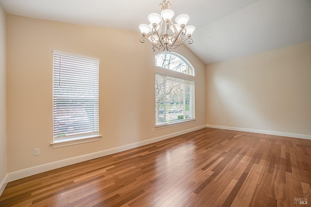 unfurnished room with baseboards, a chandelier, and wood finished floors