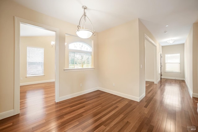 unfurnished dining area featuring dark wood-type flooring and baseboards