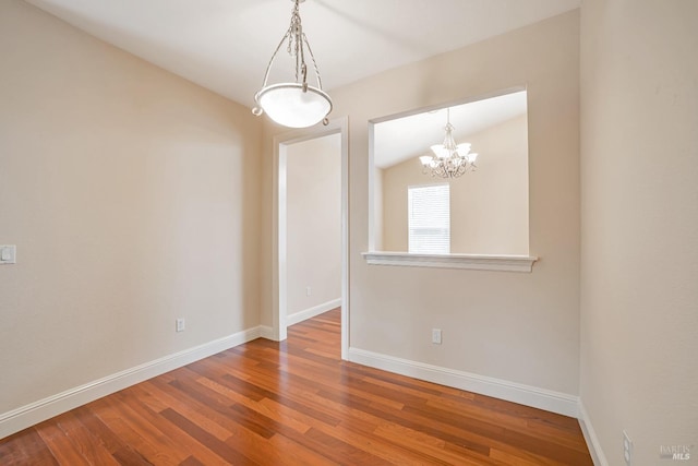 empty room with lofted ceiling, wood finished floors, and baseboards