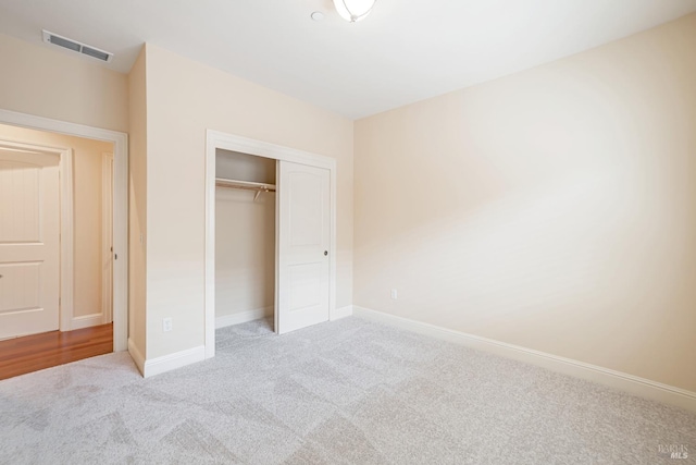 unfurnished bedroom with light carpet, a closet, visible vents, and baseboards