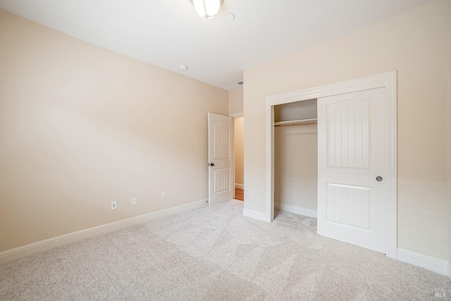 unfurnished bedroom with light carpet, baseboards, and a closet