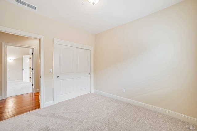 unfurnished bedroom featuring carpet floors, baseboards, visible vents, and a closet