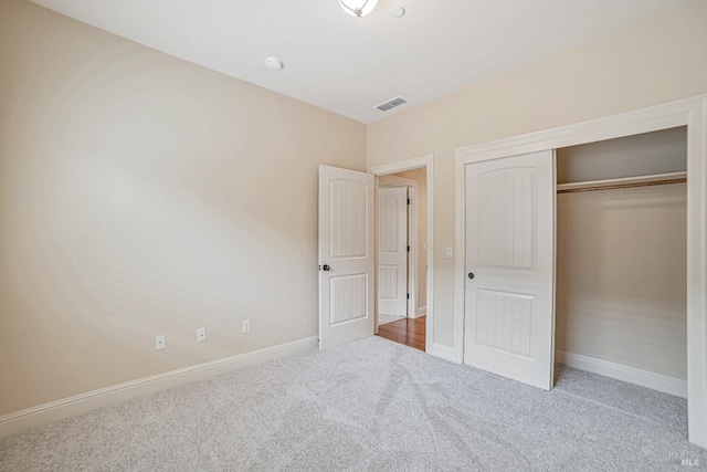 unfurnished bedroom featuring a closet, carpet flooring, visible vents, and baseboards