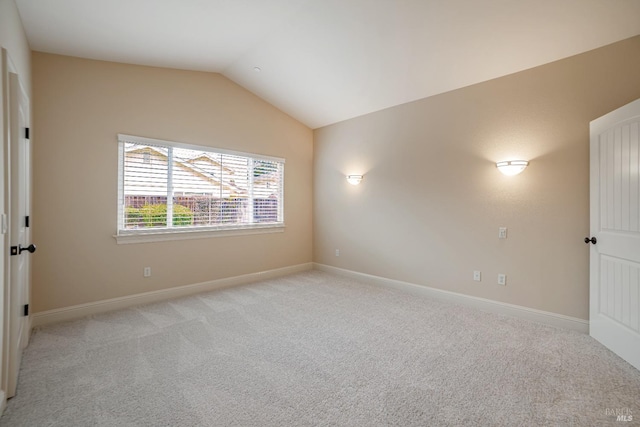 spare room with lofted ceiling, light carpet, and baseboards