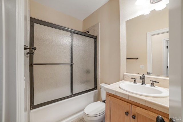 bathroom featuring toilet, bath / shower combo with glass door, and vanity