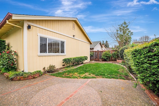 view of side of home featuring a patio area, a fenced backyard, and a lawn