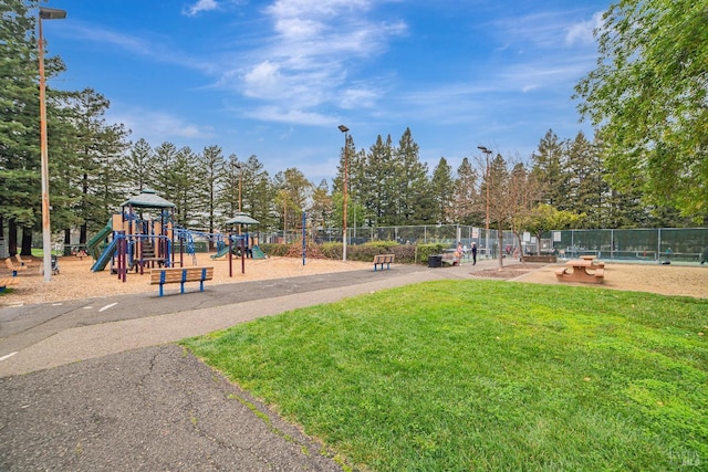 community jungle gym featuring a yard and fence