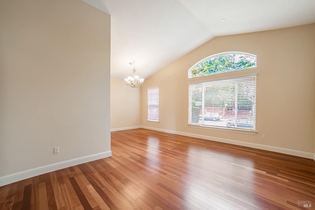 spare room with lofted ceiling, baseboards, a notable chandelier, and light wood finished floors