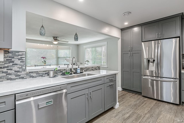 kitchen with a sink, appliances with stainless steel finishes, gray cabinets, and pendant lighting