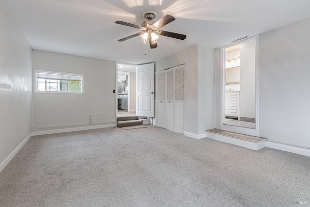 carpeted empty room with baseboards, visible vents, and ceiling fan