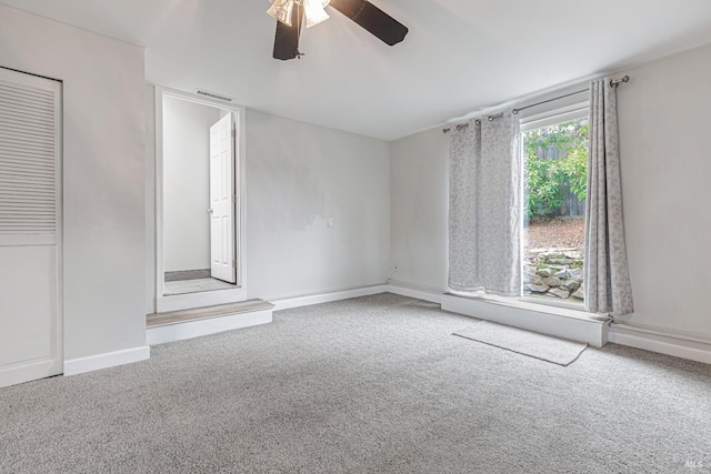 carpeted spare room featuring ceiling fan, visible vents, and baseboards