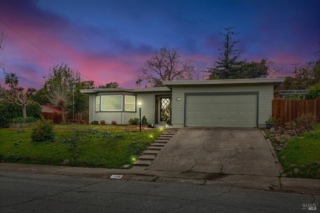 view of front of house with a front lawn, driveway, an attached garage, and fence