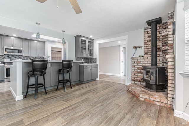 kitchen featuring glass insert cabinets, gray cabinets, appliances with stainless steel finishes, and light countertops