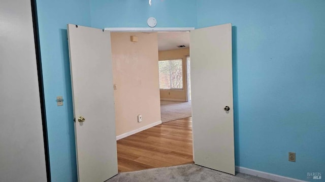 carpeted spare room with wood finished floors, visible vents, and baseboards