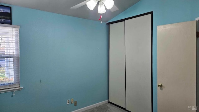 unfurnished bedroom with lofted ceiling, a closet, ceiling fan, and baseboards