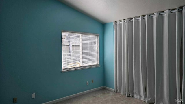 carpeted empty room with baseboards and vaulted ceiling