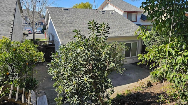 view of home's exterior featuring roof with shingles, a patio area, and fence