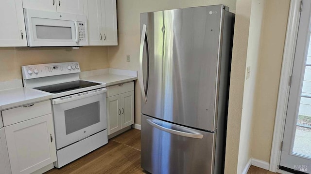 kitchen featuring white appliances, baseboards, dark wood finished floors, light countertops, and white cabinetry