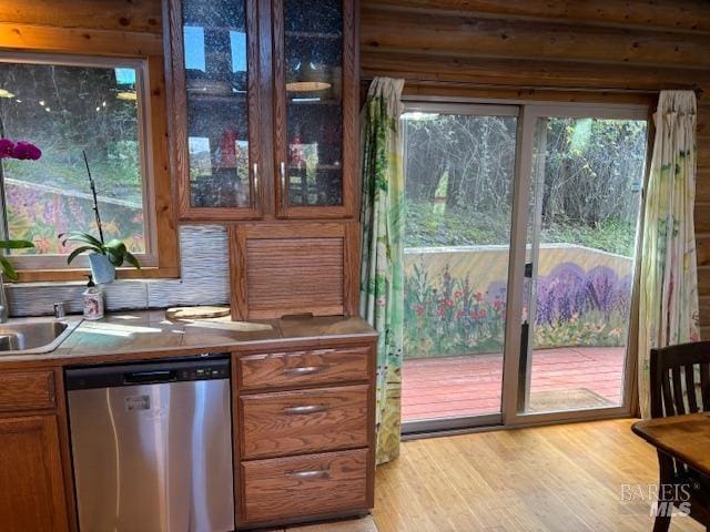 kitchen with stainless steel dishwasher, brown cabinetry, glass insert cabinets, and light wood-style flooring