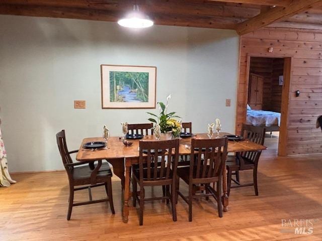 dining space with light wood finished floors and beamed ceiling