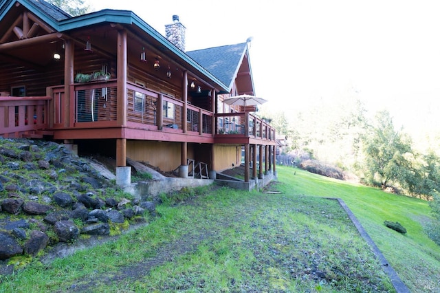 view of side of home with a chimney, a deck, and a yard