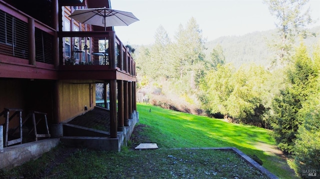 view of yard featuring a wooded view and a wooden deck