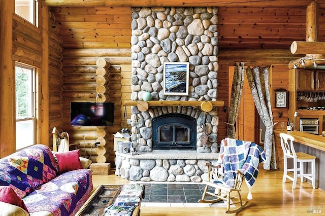 living area with high vaulted ceiling, a fireplace, log walls, and wood finished floors