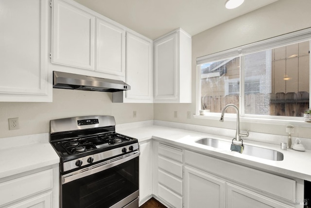 kitchen with light countertops, white cabinets, stainless steel gas stove, a sink, and under cabinet range hood