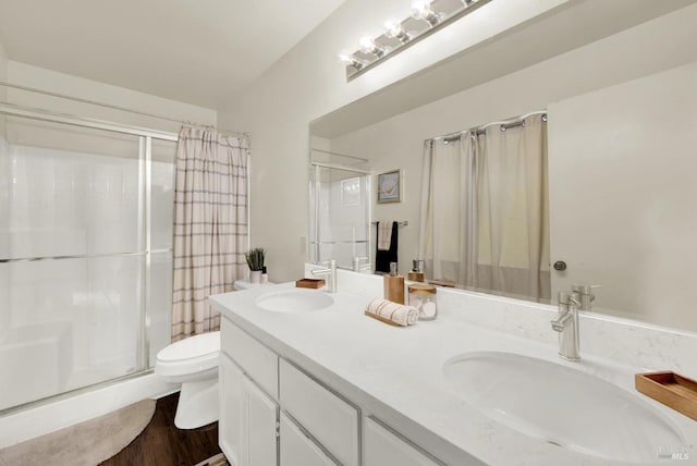 bathroom featuring a sink, a shower stall, toilet, and double vanity