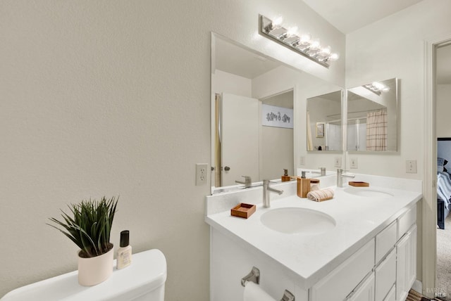 bathroom with double vanity, a sink, and toilet