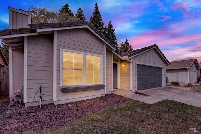 single story home featuring driveway, a lawn, and an attached garage