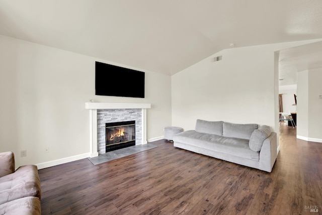 living room featuring lofted ceiling, a stone fireplace, dark wood finished floors, and visible vents