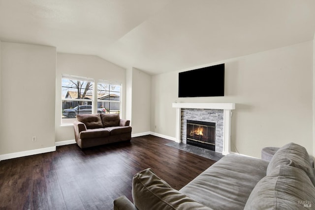 living area featuring lofted ceiling, a stone fireplace, baseboards, and wood finished floors