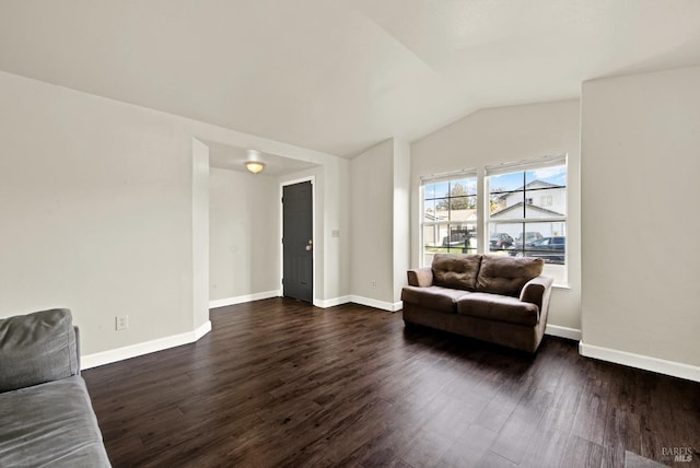 living area featuring vaulted ceiling, dark wood finished floors, and baseboards