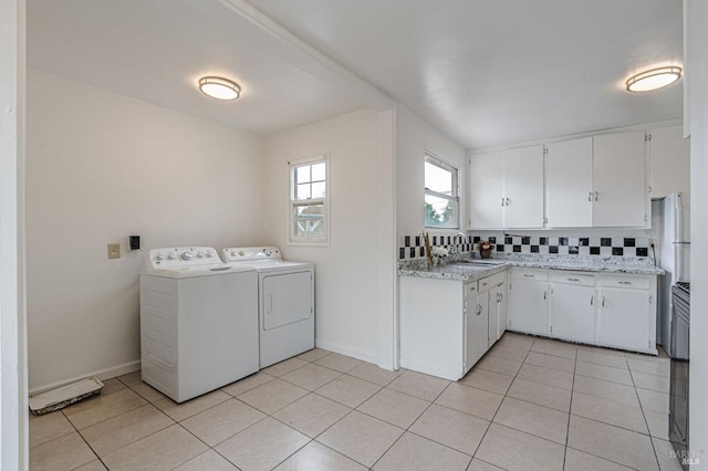 laundry room with light tile patterned floors, baseboards, washer and clothes dryer, and a sink