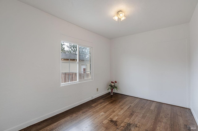 spare room with baseboards and wood finished floors