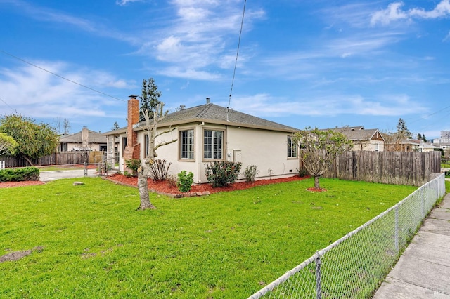 exterior space with a yard, a chimney, a fenced backyard, and stucco siding