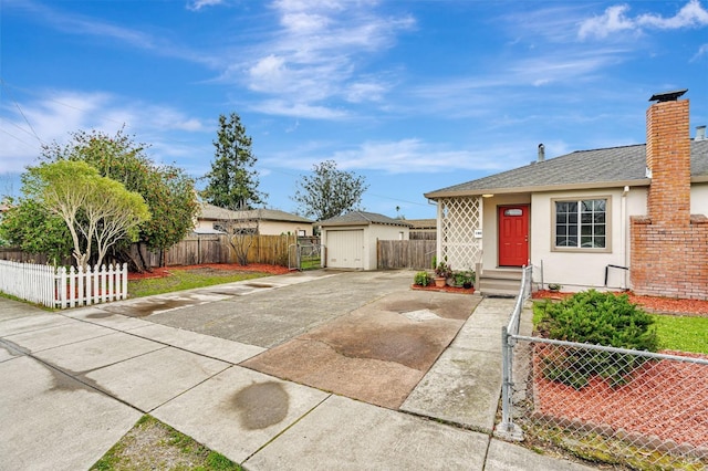 view of front of property with a fenced front yard, a detached garage, a chimney, stucco siding, and concrete driveway