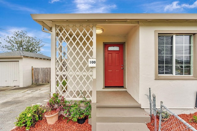 doorway to property with fence and stucco siding