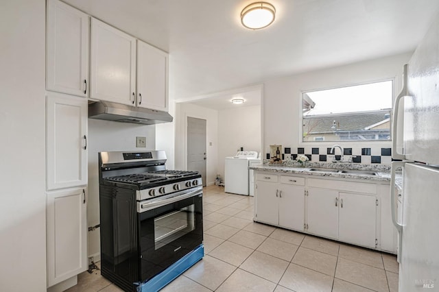 kitchen with washer / clothes dryer, freestanding refrigerator, under cabinet range hood, stainless steel range with gas cooktop, and a sink