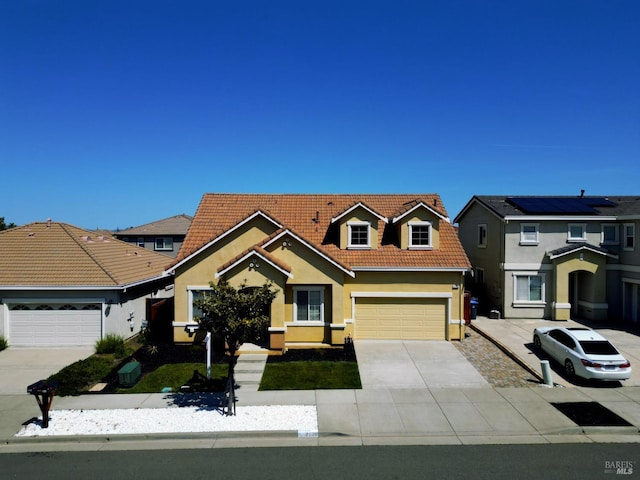 traditional home featuring concrete driveway, stucco siding, a garage, and a tile roof