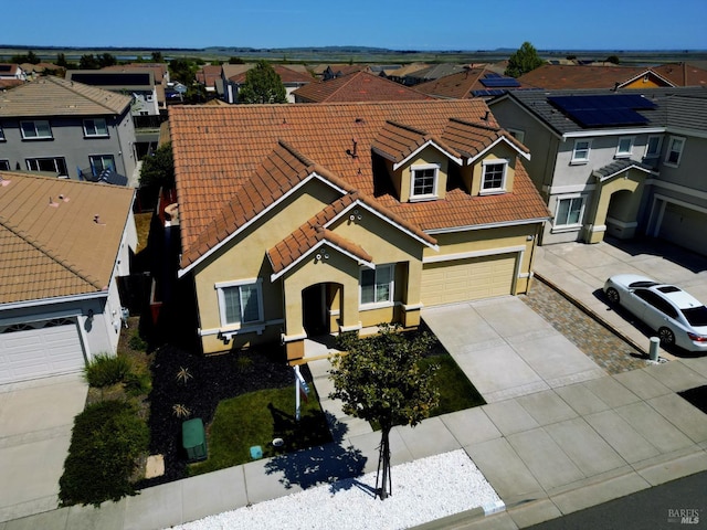 view of front of house featuring a tiled roof, a garage, concrete driveway, stucco siding, and a residential view